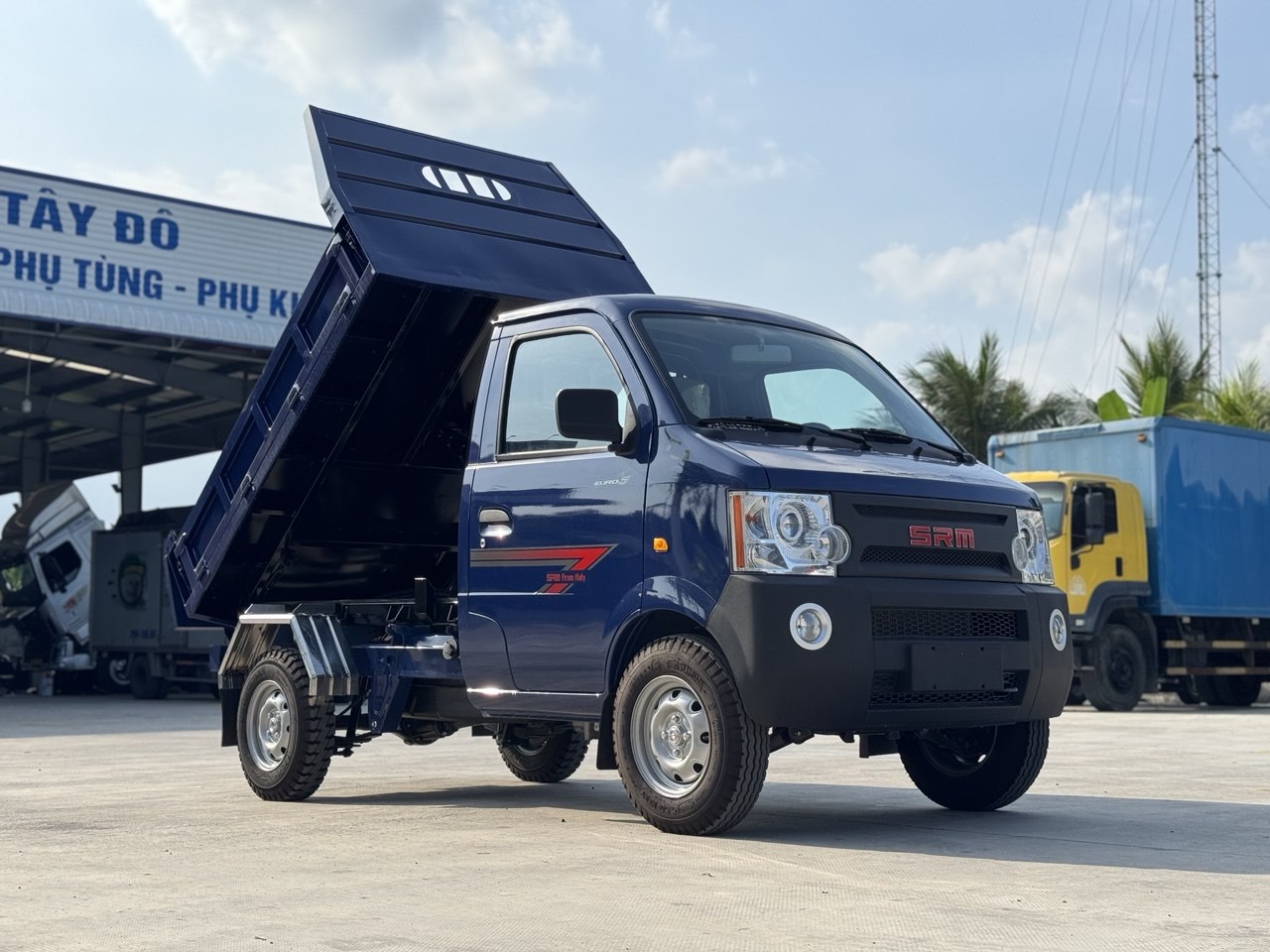 Ảnh chụp góc trước bên phải của xe ben SRM K990 màu xanh dương, thùng ben đang nâng lên