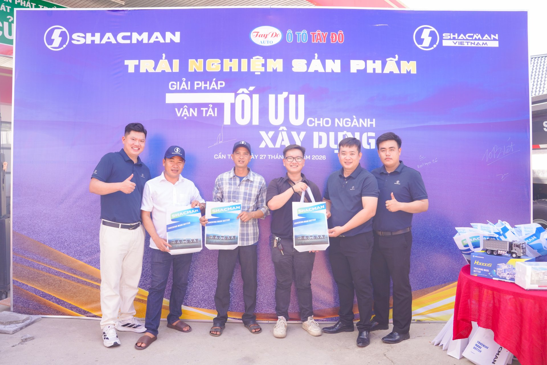 Nhóm 6 người đàn ông chụp ảnh lưu niệm trước backdrop sự kiện Shacman tại Cần Thơ